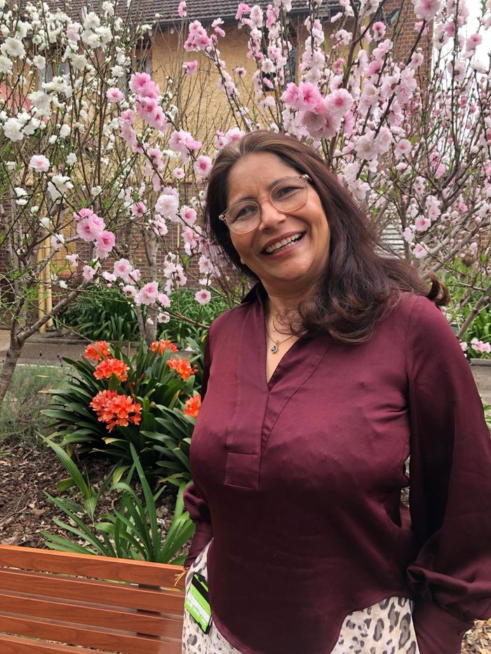 Dr Hemani Chaturvedi smiling among spring blossom in a garden